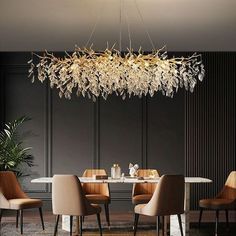 an elegant chandelier hangs over a dining room table with chairs and a plant