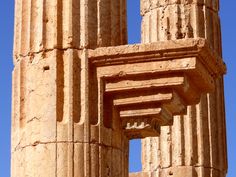 an old stone structure with columns on the side and blue sky in the back ground