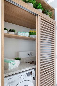 a washer and dryer in a small room with open shelves on the wall