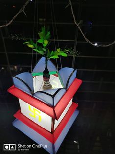 a vase with a plant on top of it hanging from strings in the dark room