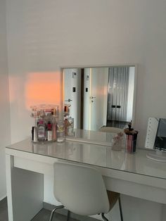 a white desk with a mirror and some bottles on it