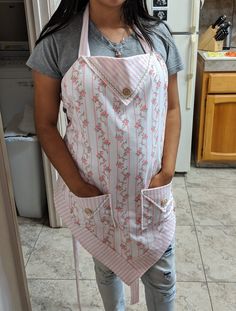 a woman standing in a kitchen holding an apron over her shoulder and smiling at the camera