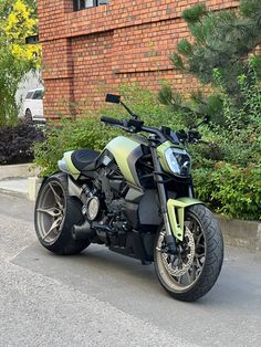 a green and black motorcycle parked in front of a brick building