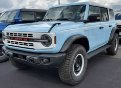 a light blue truck parked in a parking lot next to other cars and trucks behind it