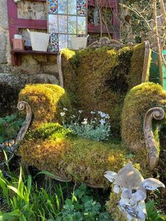 an old chair is covered in moss and flowers