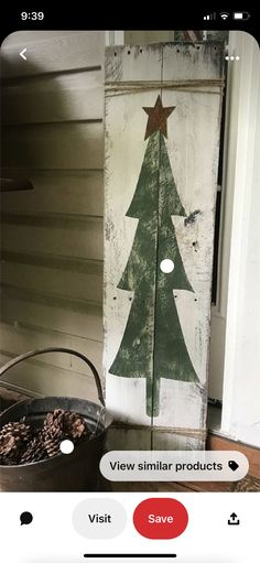 a wooden sign with a christmas tree on it next to a potted pine cone