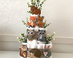 a diaper cake decorated with animals and leaves on it's sides, sitting on a table