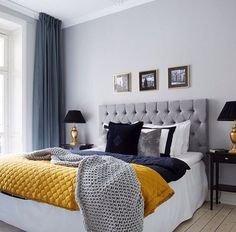 a bedroom with yellow and blue bedding, black and white pillows, and pictures on the wall