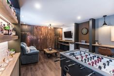 a living room filled with furniture and a foosball table in front of a flat screen tv