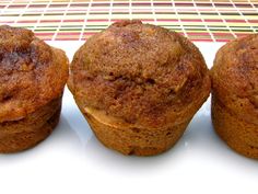 three muffins sitting on top of a white plate next to a red and yellow table cloth