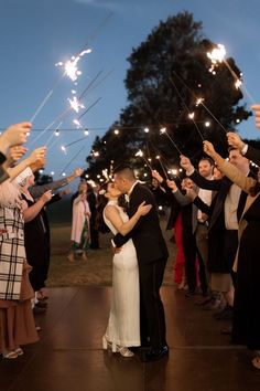 a bride and groom kissing under sparklers at their wedding