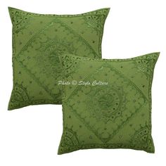 two green pillows with decorative designs on the front and back, both in different colors