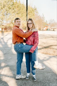 a man and woman standing next to each other in front of a street light with their arms around each other