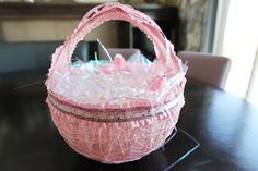 a pink basket sitting on top of a table filled with plastic wrap and pins in it