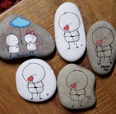 four painted rocks with cartoon characters on them, one is holding a heart and the other has an umbrella