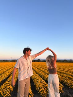 a man and woman standing in front of a field of flowers