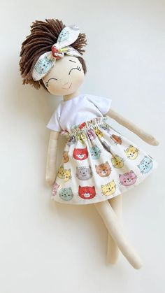 the doll is wearing a dress with cats on it's skirt and headband