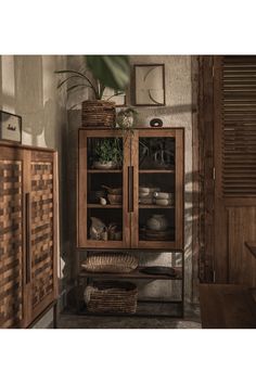 a wooden cabinet with glass doors and baskets on the top shelf in a living room