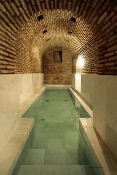 an indoor swimming pool with brick walls and water in the middle is lit by sunlight