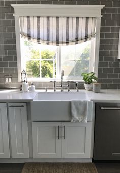 a white kitchen sink sitting under a window next to a dishwasher and oven