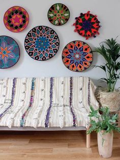 a bed sitting next to a wooden floor covered in lots of different colored plates on the wall