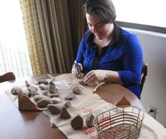 a woman sitting at a table with some rocks on it and a wire basket in front of her