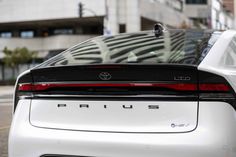 the rear end of a white car parked in front of a building