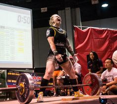 a woman is standing on a barbell with her mouth open