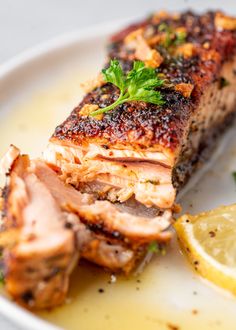 a piece of meat on a plate with lemon wedges and parsley garnish