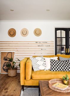 a living room with yellow couches and hats on the wall above them is a coffee table