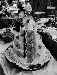 black and white photograph of a wedding cake on a table with people in the background