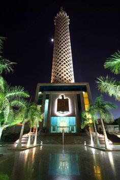 a tall tower with a clock on it's side next to some palm trees