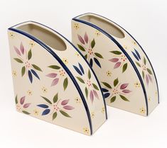 two ceramic vases with floral designs on them sitting next to each other in front of a white background