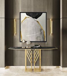 a modern console table with an abstract painting on the wall behind it and gold accents