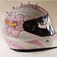 a helmet with spikes on the side and flowers painted on it, sitting on a white surface