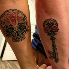 two people with tattoos on their legs and one is holding a key to the other side