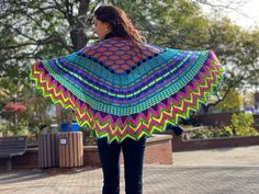 a woman is walking down the street wearing a colorful shawl