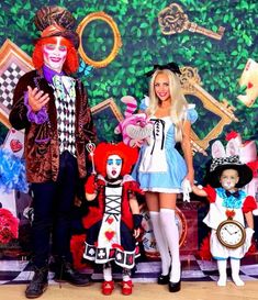 three people dressed in costumes posing for a photo with clowns and other characters behind them