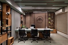 an office with two desks and chairs in front of a book shelf filled with books