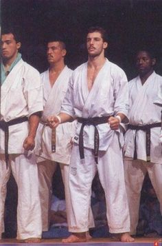 a group of men standing next to each other on top of a stage holding black belts