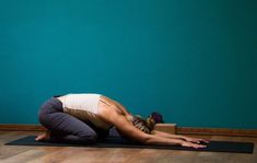 a woman is doing yoga in front of a blue wall