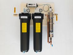 two water filtrators sitting next to each other on a white surface with yellow labels