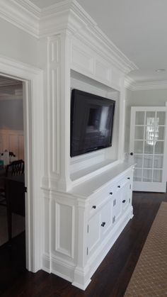 a flat screen tv mounted to the side of a white wall in a living room