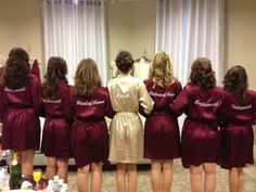 a group of women standing in front of a mirror wearing maroon robes and matching shoes