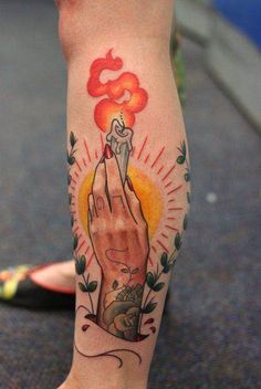 a person with a tattoo on their leg holding a lit candle in one hand and an open flame in the other