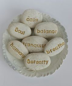 some rocks with words written on them sitting in a glass bowl that says calm, balance, tranquilly, breathe and serenity