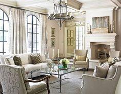 a living room filled with furniture and a chandelier hanging from the ceiling over a fire place