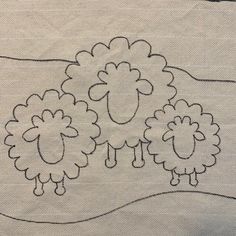 two sheep are standing in the middle of a white cloth with black stitching on it