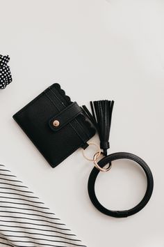 a small black purse with a ring on top of it next to a hair tie