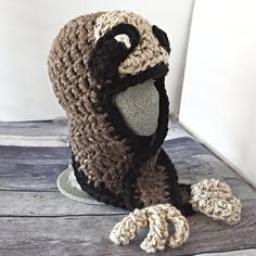 a crocheted dog sits on top of a wooden table wearing a knit hat